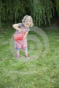 Little girl with watering can in the garden