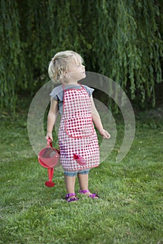 Little girl with watering can in the garden