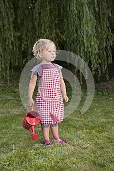 Little girl with watering can in the garden