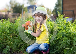 Little girl watering with can in the vegetables