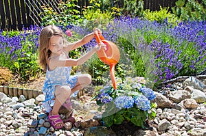 Little girl watering flowers in a garden