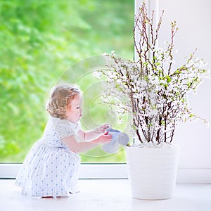 Little girl watering flowers at home