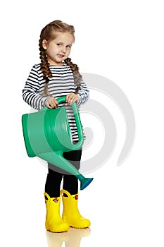 A little girl is watering a garden.
