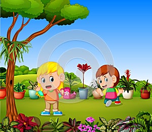 Little girl watering plants and a boy planting in a garden