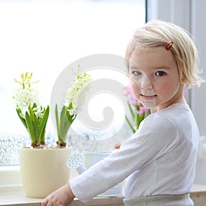 Little girl watering spring flowers at home