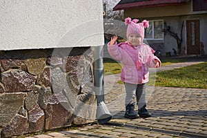 little girl waving her hand in autumn,girl near her house says goodbye in autumn