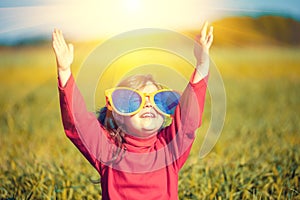 Little girl wearing big sunglasses looking at the sun