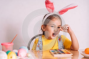 Little girl wearing bunny ears on her head eats chocolate from a spoon