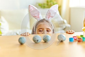 Little girl wearing bunny ears playing egg hunt on Easter