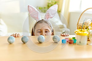 Little girl wearing bunny ears playing egg hunt on Easter
