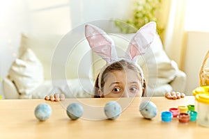 Little girl wearing bunny ears playing egg hunt on Easter