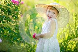 A little girl wearing flower yellow dress with white hat and stand in the yellow flower field of Sunn Hemp Crotalaria