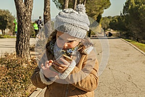 Little girl wearing grey bonnet and jeans with a smartphone