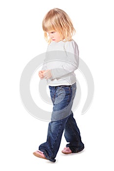 Little girl wearing jeans and shirt is walking