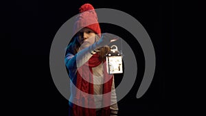 Little girl wearing knitted winter hat and scarf walking with lantern