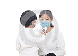 A little girl wearing a mask is measuring her mother`s temperature with a thermometer in hand