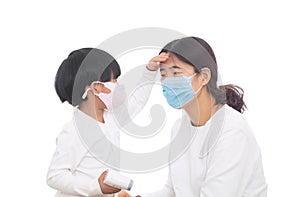 A little girl wearing a mask is measuring her mother`s temperature with a thermometer in hand