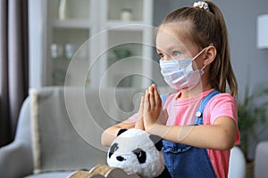Little girl wearing mask for protect Covid-19. She praying in the morning for a new day freedom to world corona virus