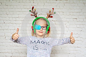 Little girl wearing occluder and Christmas raindeer horns, treatment of amblyopia and poor eyesight