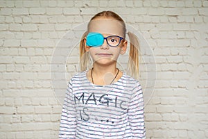 Little girl wearing occluder and eyeglasses, treatment of amblyopia and poor eyesight