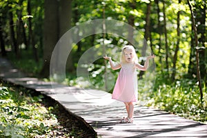 Little girl wearing pink dress taking a walk all alone