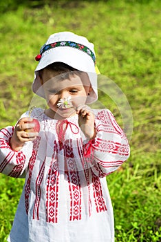 Little girl wearing a traditional Romanian blouse named ie and smelling a flower