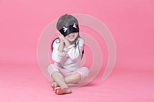 Little girl wearing white pajamas and black eyemask photo