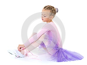 Little girl wears ballet shoes.