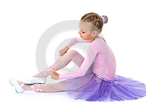 Little girl wears ballet shoes.