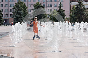 Little girl in wet dress roller skates in fountain in summ