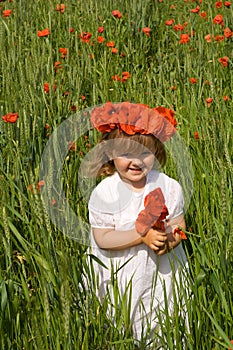 Little girl on wheat field with poppies