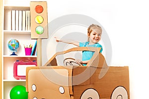 Little girl at the wheel of handmade cardboard car