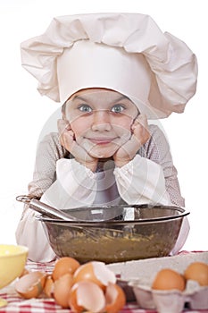 Little girl in a white apron breaks near the plate with eggs