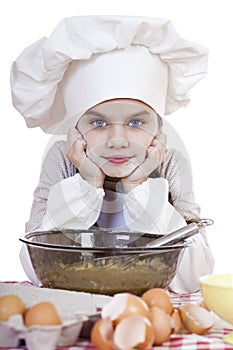 Little girl in a white apron breaks near the plate with eggs