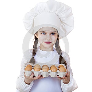 Little girl in a white apron breaks near the plate with eggs