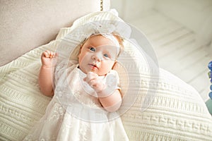 little girl with a white bow lies on the couch, on a white background.