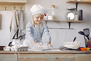 Little girl in a white chef hat cook the dough for cookies