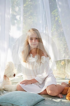 Little girl in white chiffon tent with toy