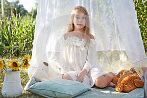 Little girl in white chiffon tent with toy