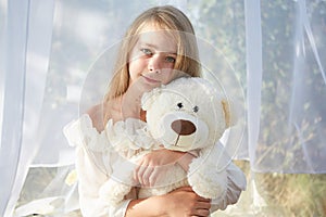 Little girl in white chiffon tent with toy