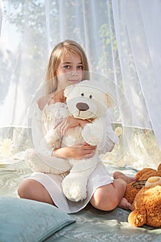 Little girl in white chiffon tent with toy