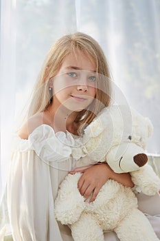 Little girl in white chiffon tent with toy