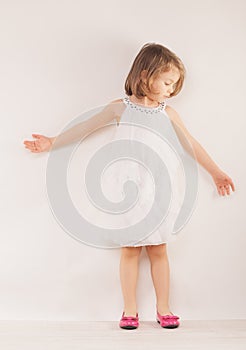 Little girl in white dress and pink shoes