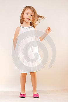 Little girl in white dress and pink shoes