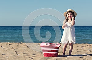 Little girl in white dress walking alone the sea, playing on the seashore