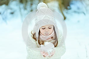Little girl in a white fur coat in the winter forest