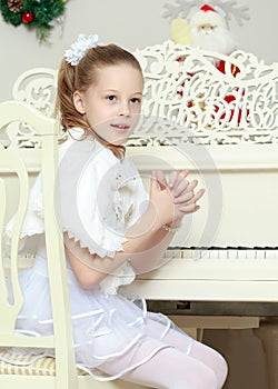 Little girl at a white Grand piano.