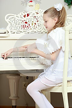 Little girl at a white Grand piano.