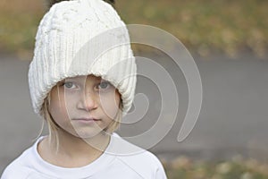 Little girl in a white hat closeup sad looks. Copy space