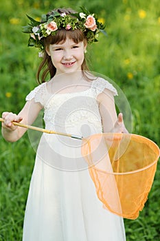Little girl in white holds orange butterfly net on